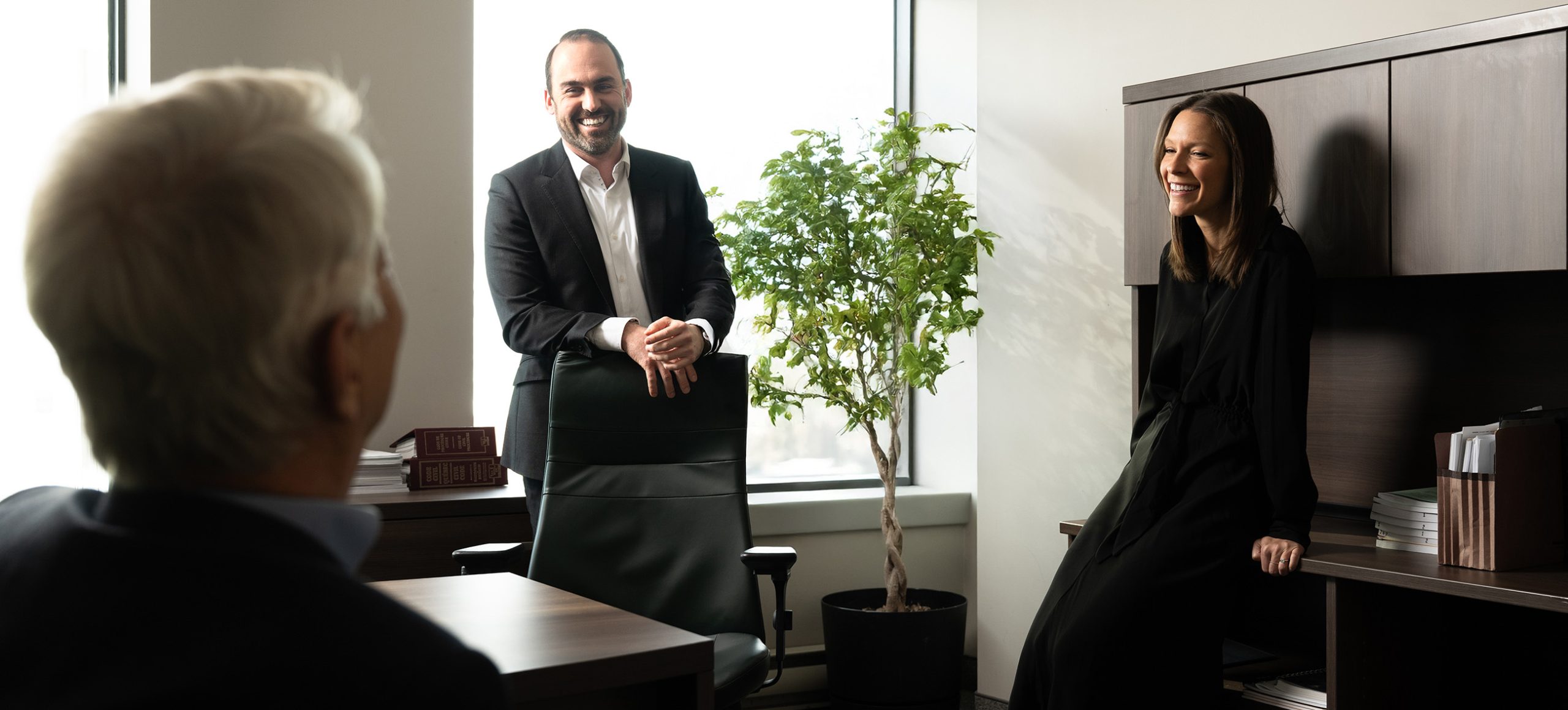 Deux hommes et une femme debout dans un bureau, souriant